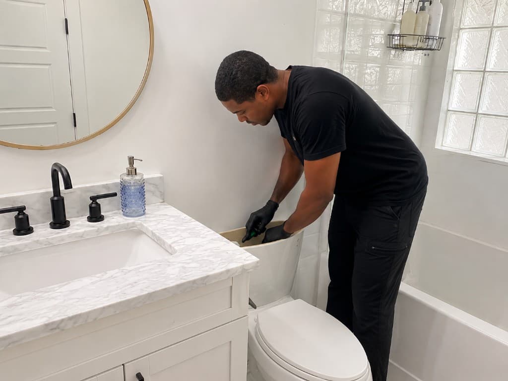 Plumber repairing a toilet tank in a modern residential bathroom
